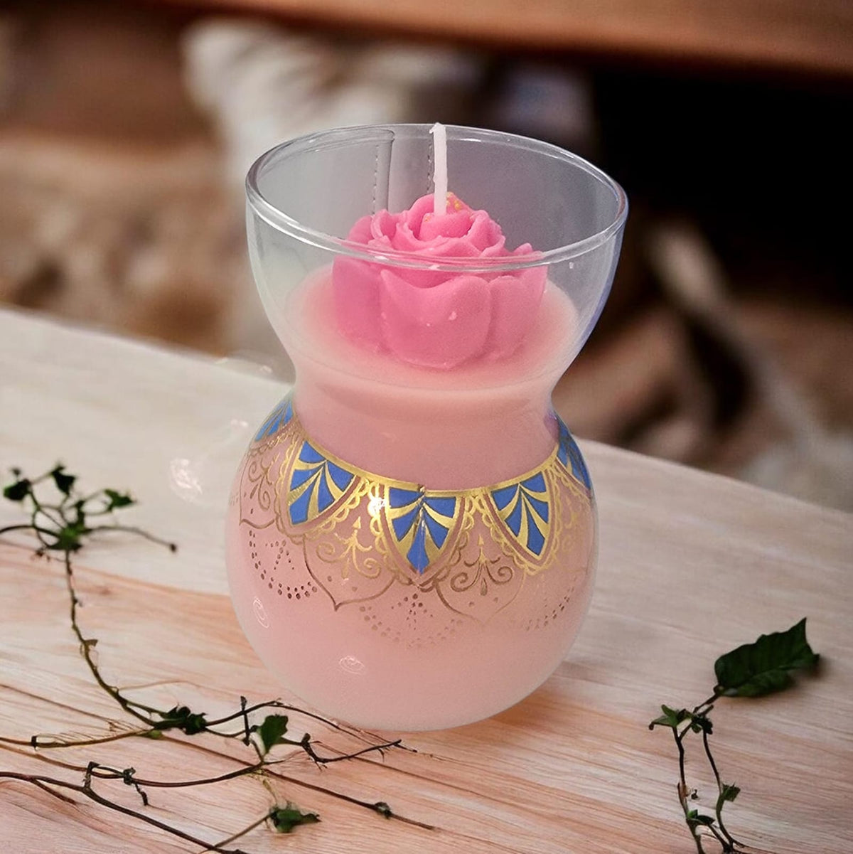 Decorative candle with pink rose design in a glass holder.